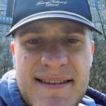 Front-facing photo of a man wearing a cap showing a visible mole on his face before removal procedure